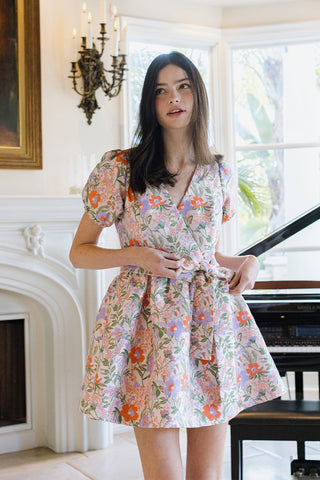 Woman wearing a floral dress in a room with a fireplace and piano.